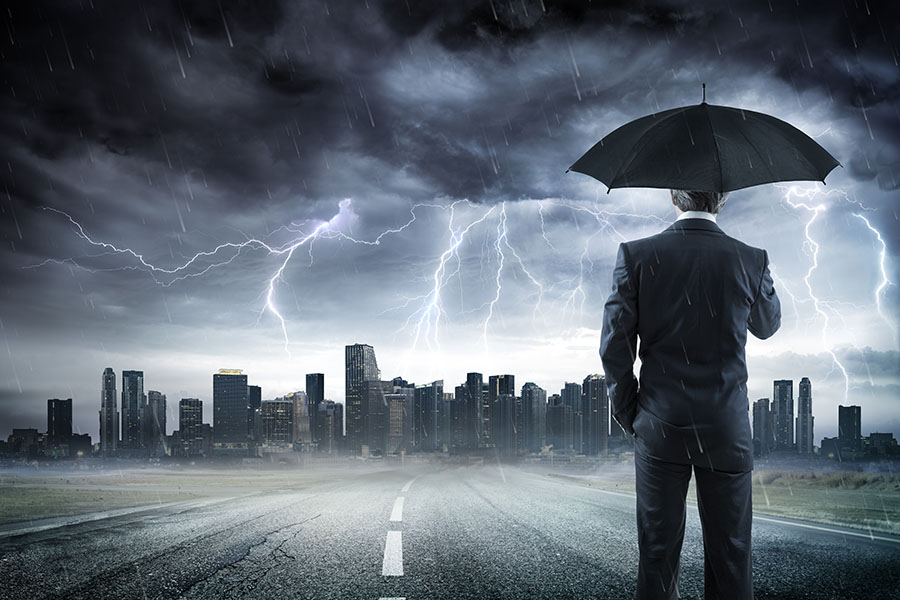 Commercial Umbrella Insurance - View of Businessman Standing on the Street Holding an Umbrella Looking at the City