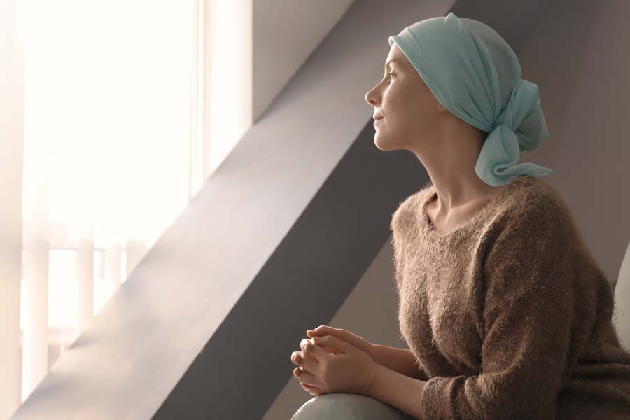 Critical Illness Insurance - A Woman with Cancer Sitting and Looking Out a Hospital Window